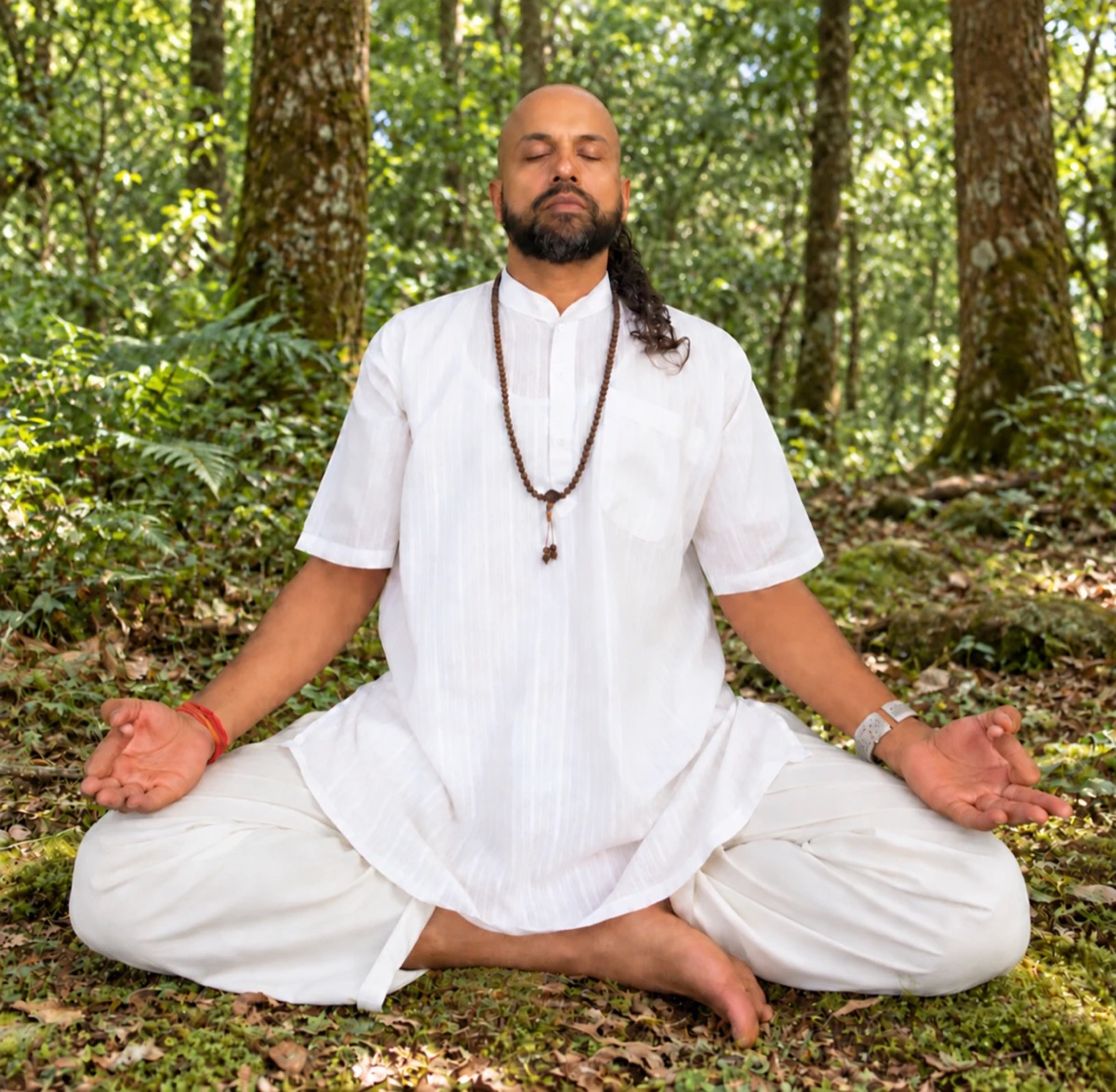 Anup meditating cross-legged in a forest, eyes closed, in a white kurta